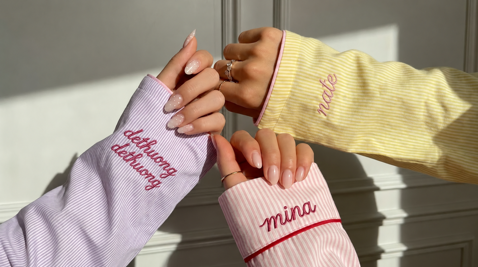 Close-up of three pastel striped pajama cuffs with personalized embroidered names and phrases